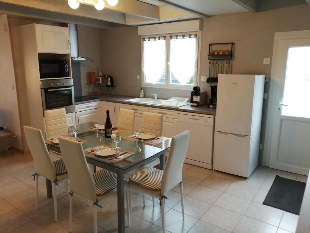 een keuken met een tafel en stoelen en een koelkast bij La Glycine in Fouesnant