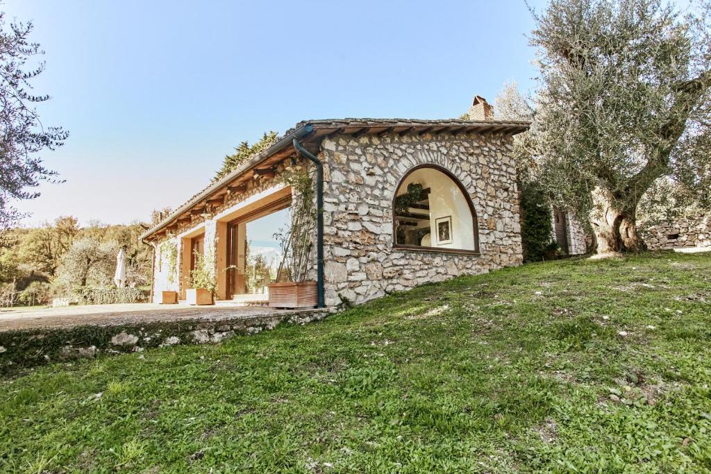 una casa in pietra con una grande finestra su un prato di Umbria Luxury Villa Pool&OliveTrees a Penna in Teverina