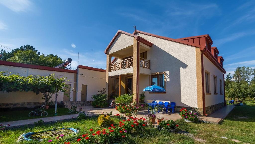 a house with a balcony and a yard with flowers at Sweet Alvani in Akhmety