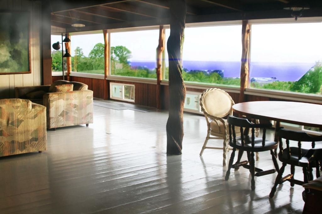 a dining room with a table and chairs and windows at Aeolian Ranch in Kailua-Kona