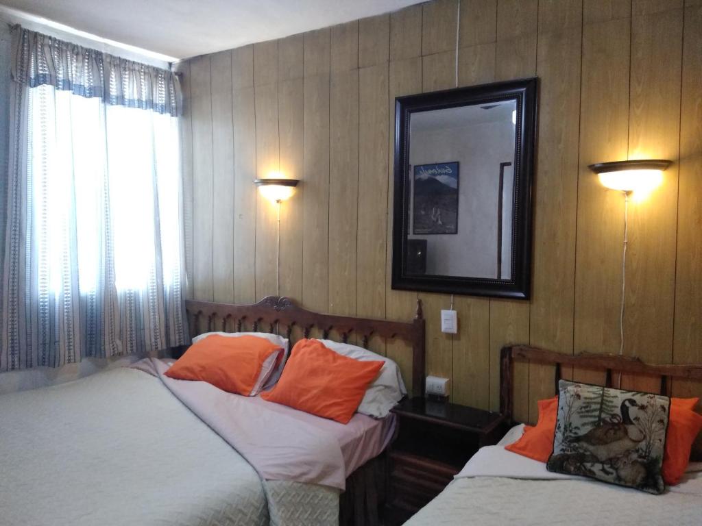 een slaapkamer met 2 bedden en een spiegel aan de muur bij Hotel Metropolitano in Guatemala