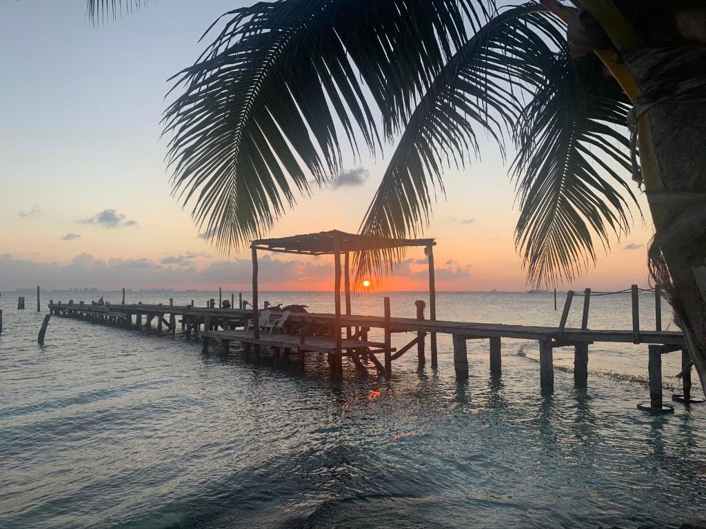 a pier on the beach with a sunset in the background at Casa Bonita and villas in Isla Mujeres