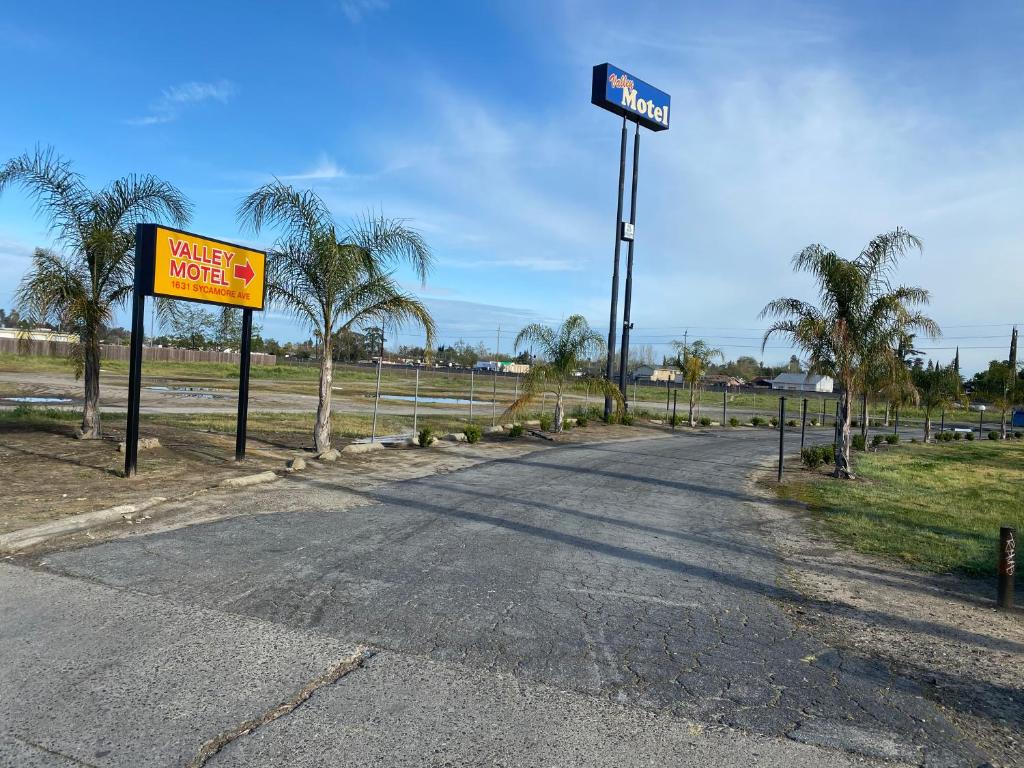 an empty road with a motel sign and palm trees at Valley Motel in Atwater