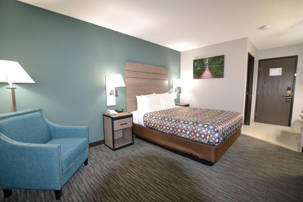 Habitación de hotel con cama y silla azul en Countryside Inn & Suites Omaha East-Council Bluffs IA en Council Bluffs