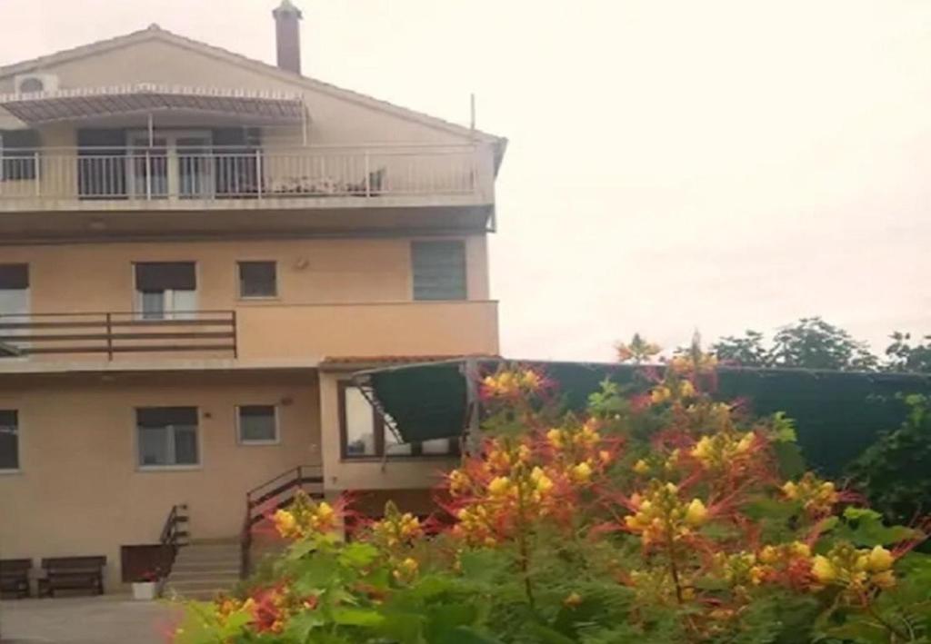un bâtiment avec un balcon et un arbre dans l'établissement Apartments and rooms Ognjen - family apartments with free parking, à Betina