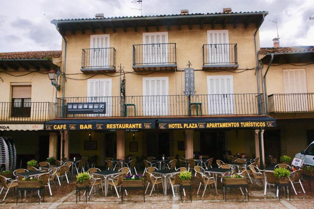 a group of tables and chairs in front of a building at Hotel plaza in Riaza