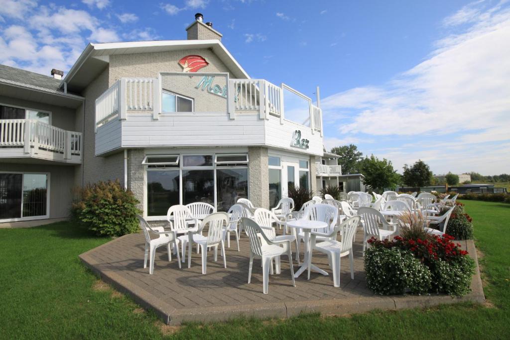 a group of white chairs and tables in front of a building at Motel Grand-Pré Inc in Bonaventure