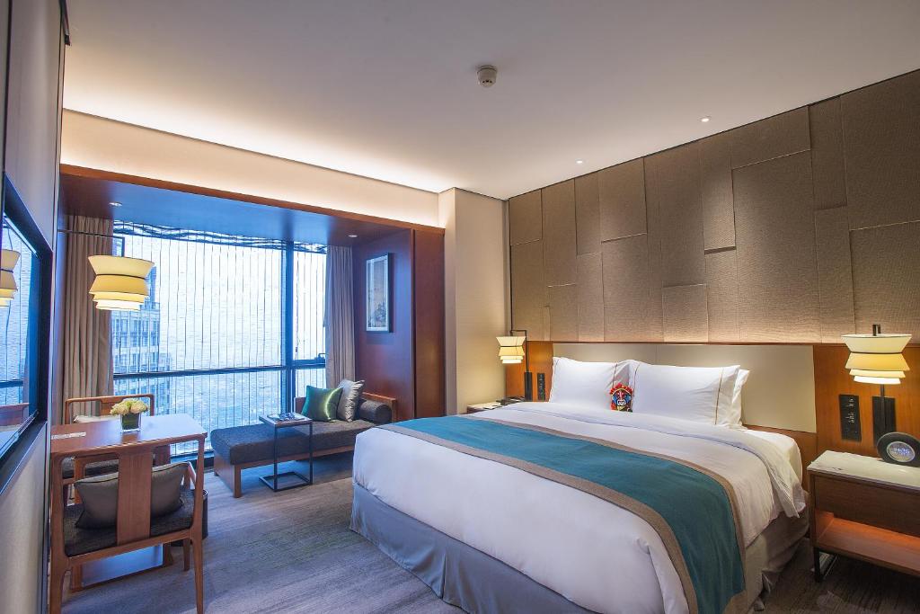 Una habitación de hotel con una cama grande y un escritorio. en Yuluxe Hotel Chengdu, en Chengdú