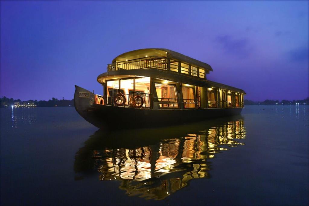 a house boat on the water at night at Cosy Premium Houseboats in Alleppey