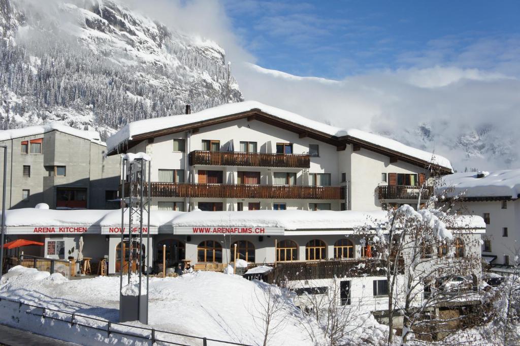 un hotel en la nieve frente a una montaña en Arena Lodge en Flims