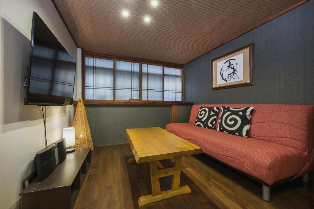 sala de estar con sofá rojo y TV en Shiki Homes NENE en Kyoto