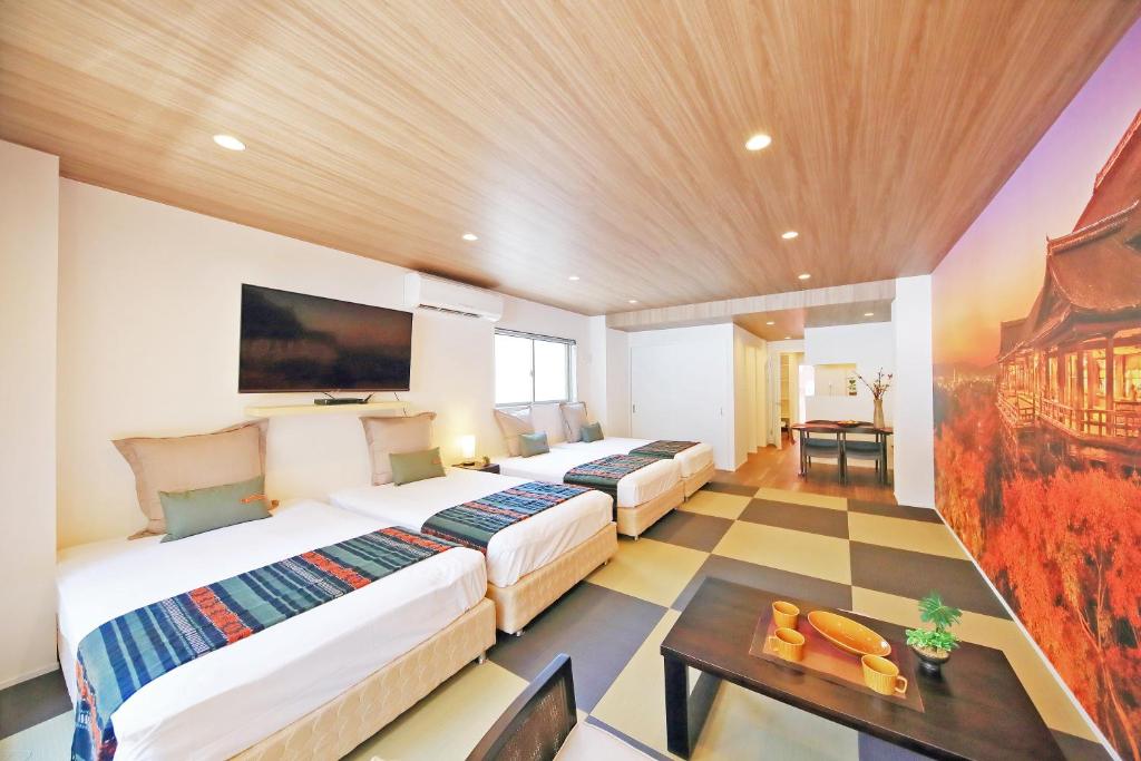 大阪市にあるカーサコモダ難波のベッド2台とテーブルが備わるホテルルームです。