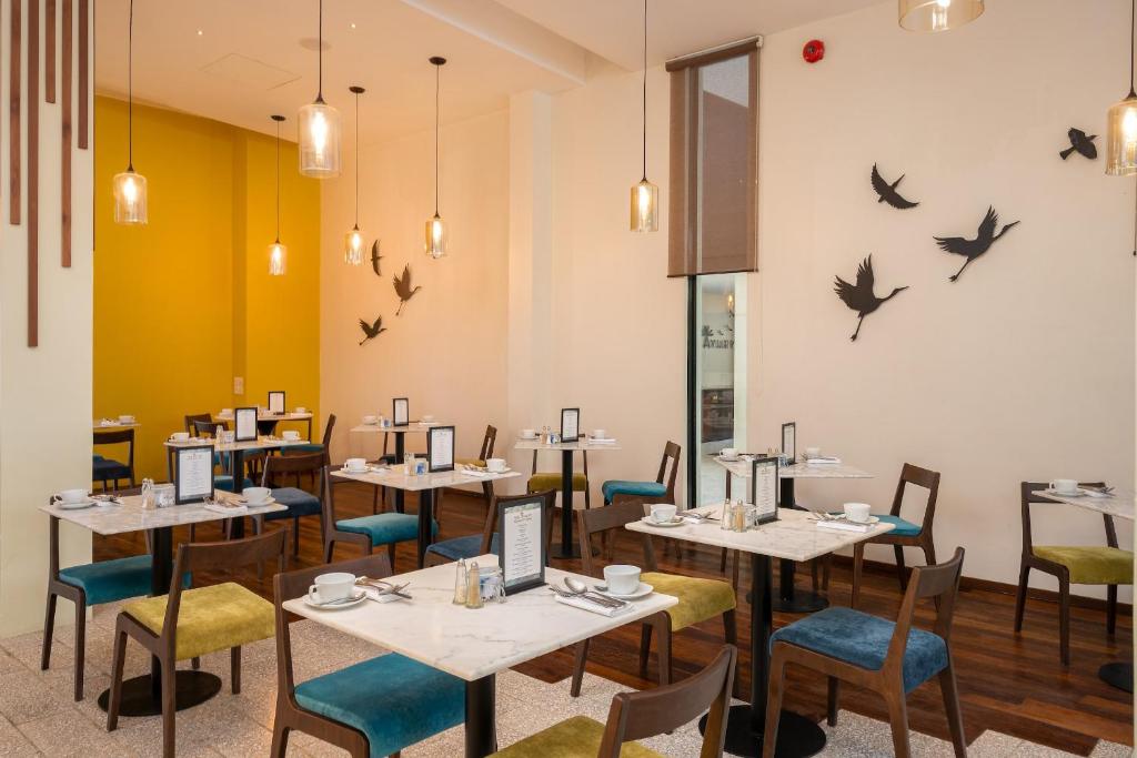 a dining room with tables and chairs and birds on the wall at The Aviary Hotel in Siem Reap