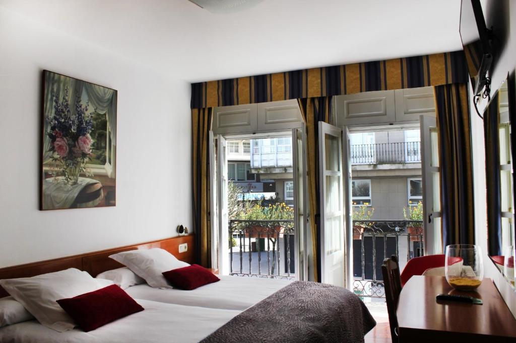 sypialnia z łóżkiem, stołem i oknami w obiekcie Hotel Hórreo by Bossh! Hotels w Santiago de Compostela