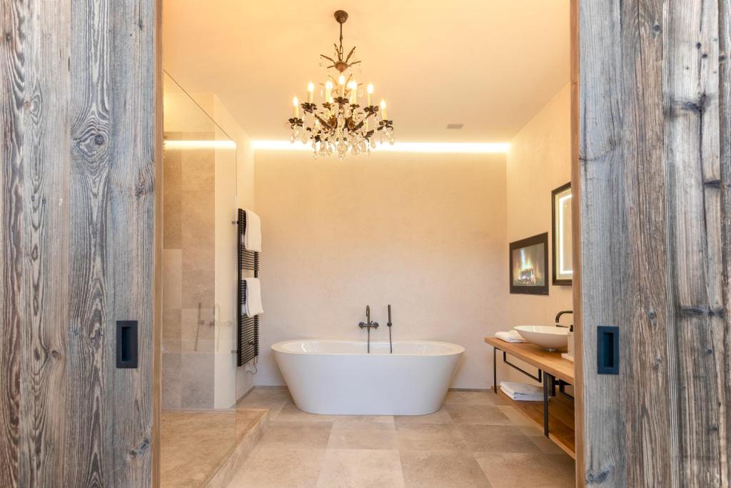 a bathroom with a large tub and a chandelier at Kitzhof Mountain Design Resort in Kitzbühel