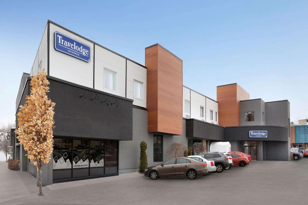 a building with cars parked in a parking lot at Travelodge by Wyndham Alma in Alma