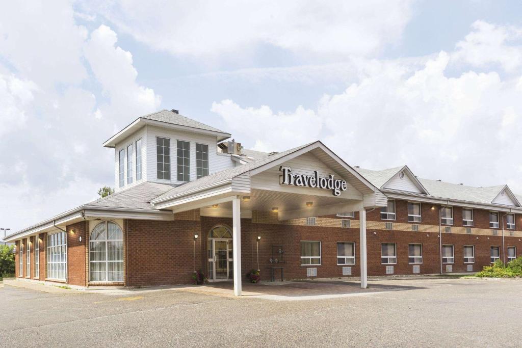 un gran edificio de ladrillo con un letrero de farmacia. en Travelodge by Wyndham Timmins en Timmins