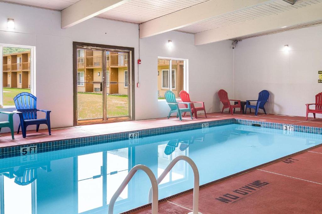 a swimming pool with colorful chairs and a table at Pocono Inn & Banquet - Stroudsburg in Delaware Water Gap