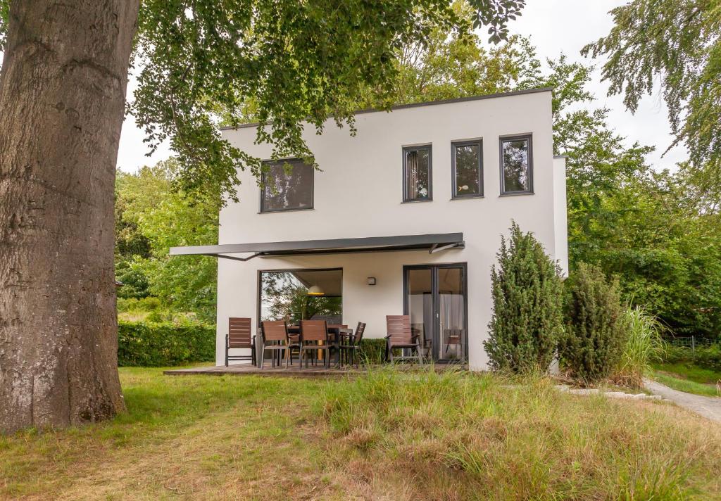 uma casa branca com uma grande árvore em die Strandhäuser - Wolkenlos em Ostseebad Sellin