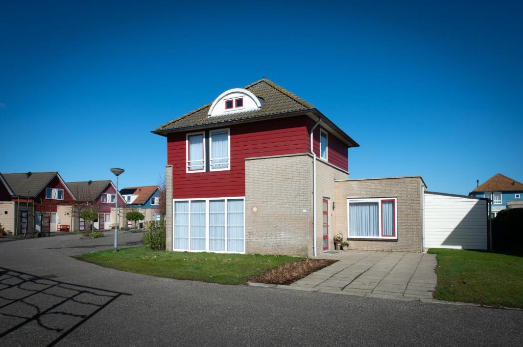 uma casa vermelha com uma garagem branca em Maxime 203 - Kustpark Village Scaldia em Hoofdplaat