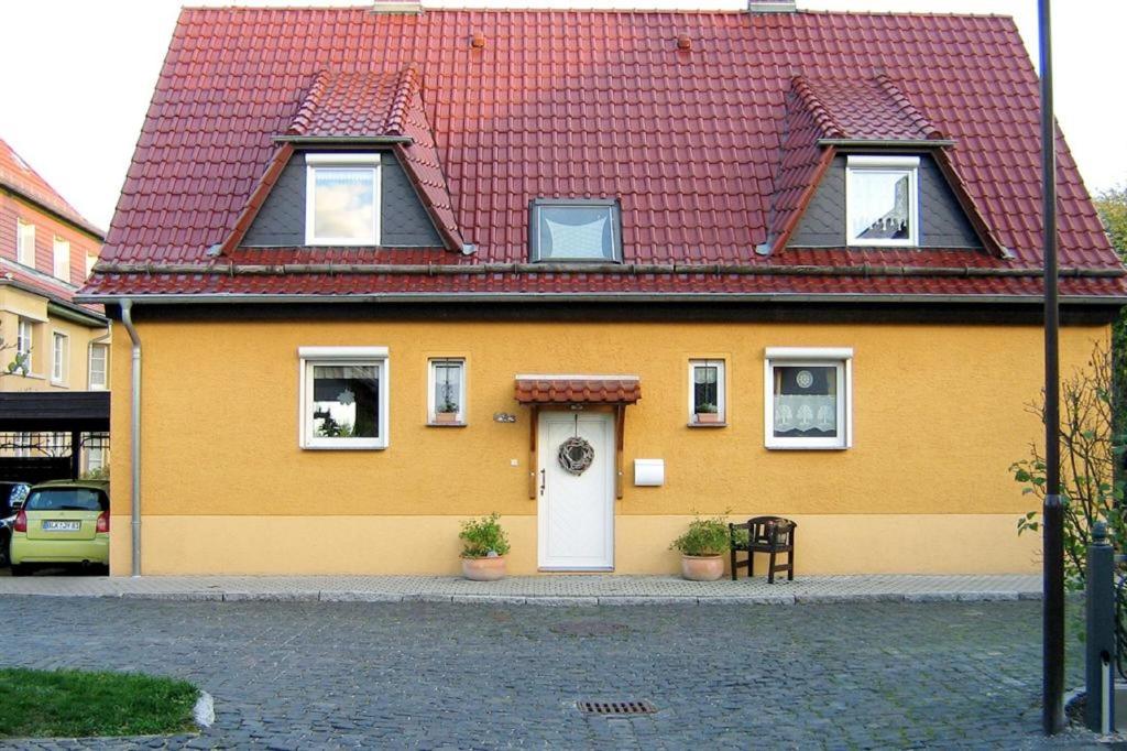 een geel en rood huis met een rood dak bij Ferienwohnung Tschitschmann in Naumburg