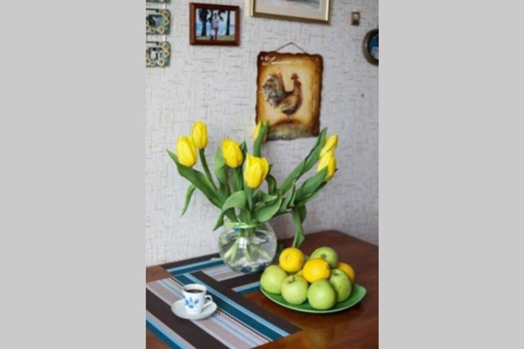 a table with a vase of flowers and a plate of fruit at Family apartment in the heart of Rivne in Rivne