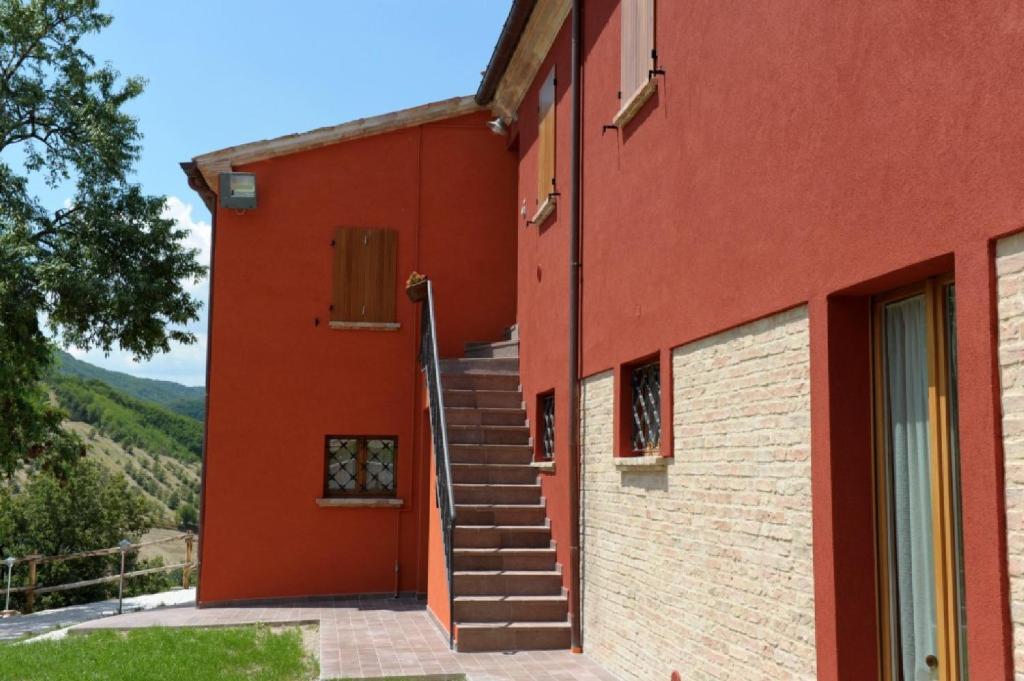 un bâtiment rouge avec des escaliers sur son côté dans l'établissement Guest house Agriturismo i Conti CIR 16277, à Urbania