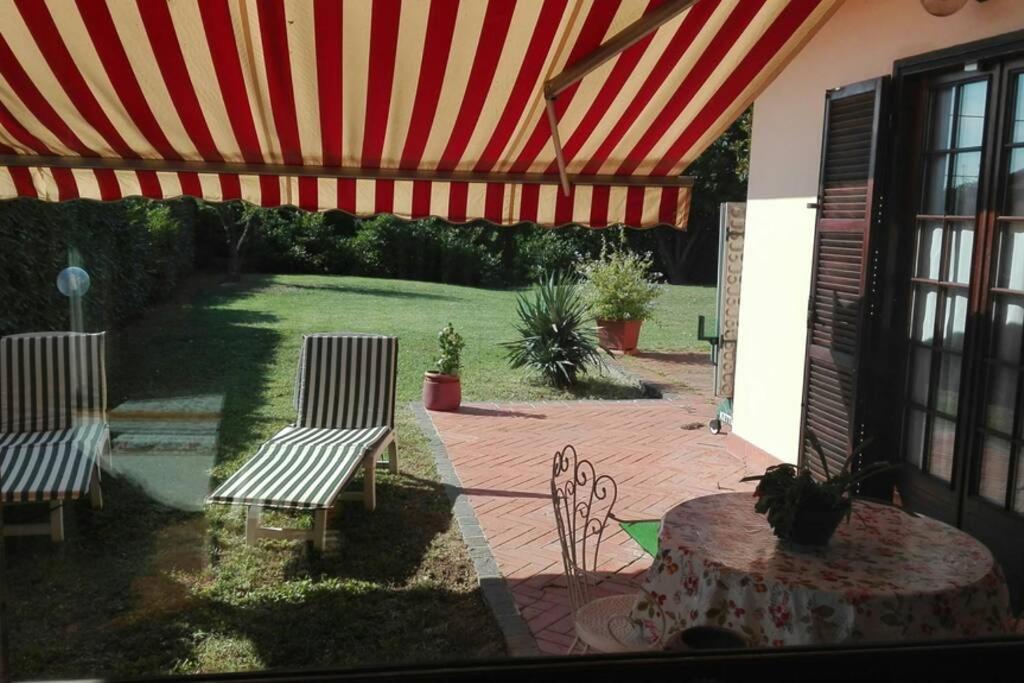 un patio con 2 sillas y una mesa bajo una sombrilla roja en Alloggio nella Villa dell'Edera, en Acqui Terme