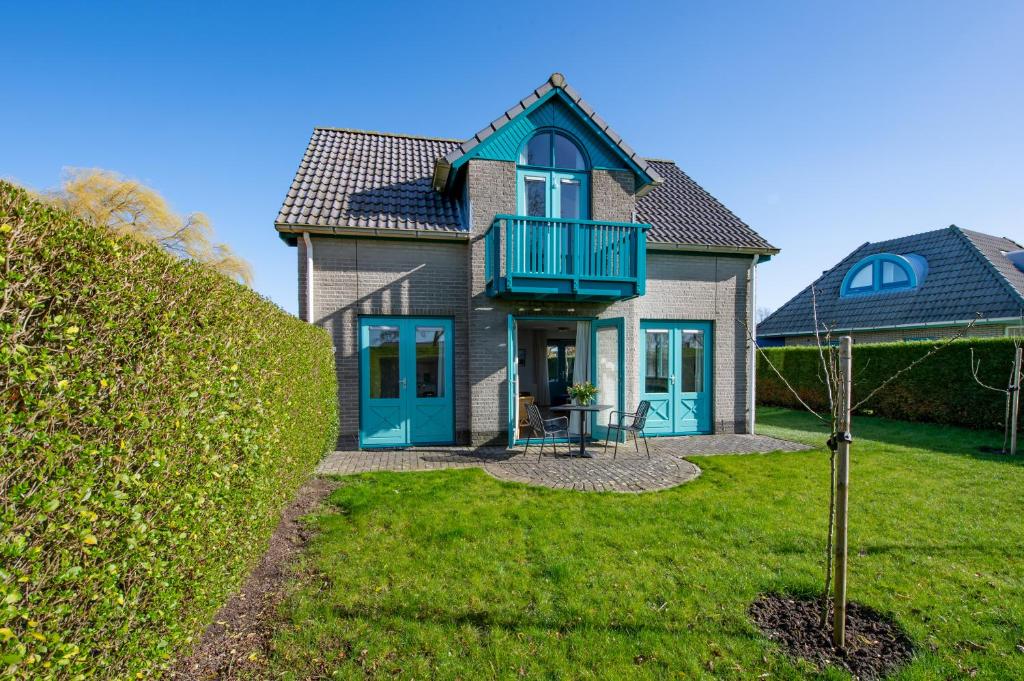 a house with blue doors and a balcony at Fréjus 116 - Kustpark Village Scaldia in Hoofdplaat