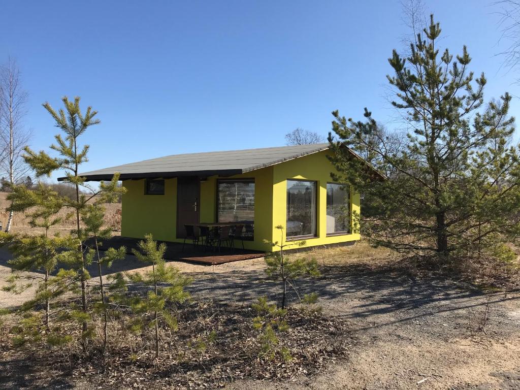 uma pequena casa amarela num campo com árvores em SKY Ranch em Izborsk