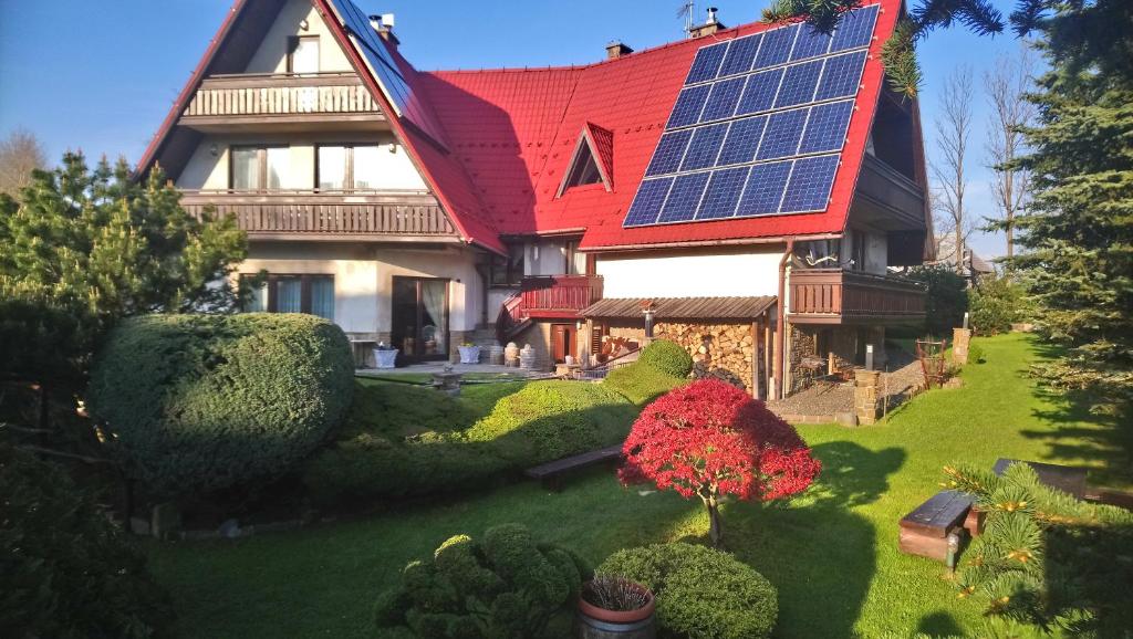 a house with a red roof with solar panels on it at Apartamenty-Wynajem pokoi Zbigniew Tylka in Kościelisko