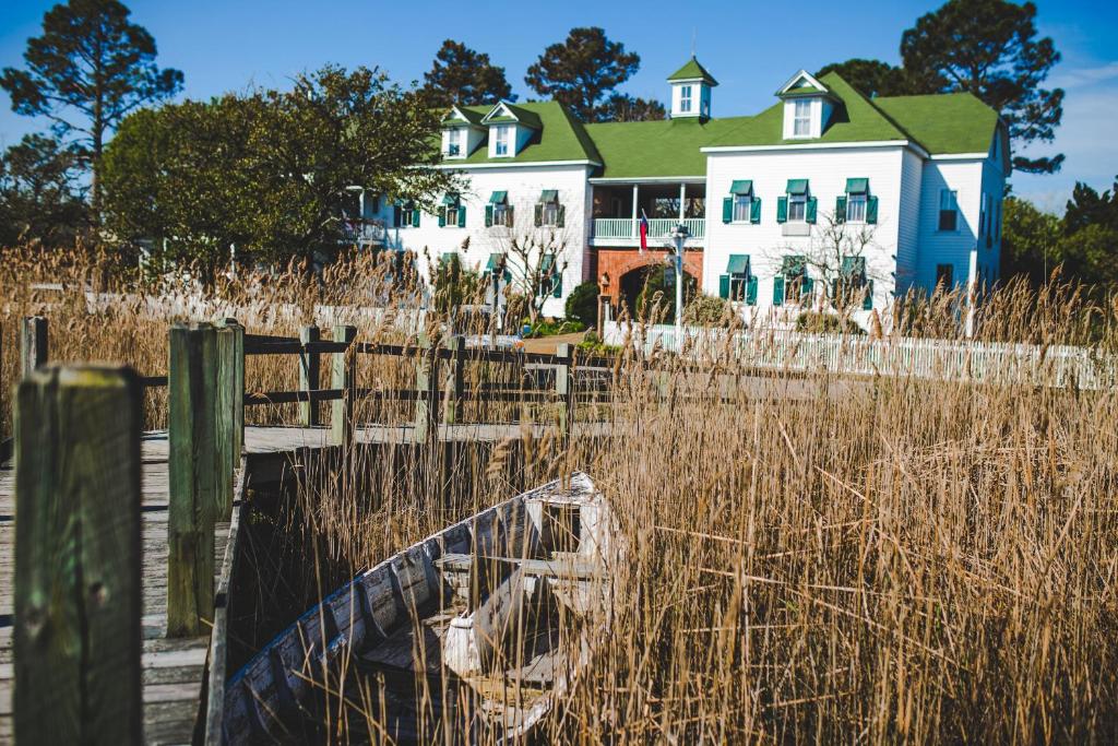 a house on the beach with a boat in the grass at Roanoke Island Inn in Manteo