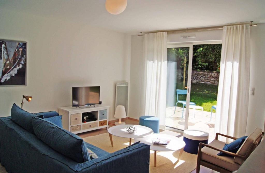 uma sala de estar com um sofá azul e uma televisão em Rivage, Belle villa à Carnac Plage em Carnac