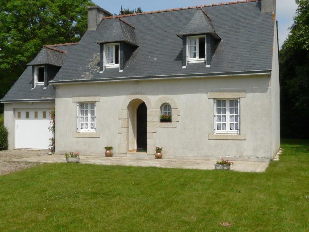 ein weißes Haus mit einem grauen Dach und einem Hof in der Unterkunft Laraon, maison à Pouldreuzic in Pouldreuzic