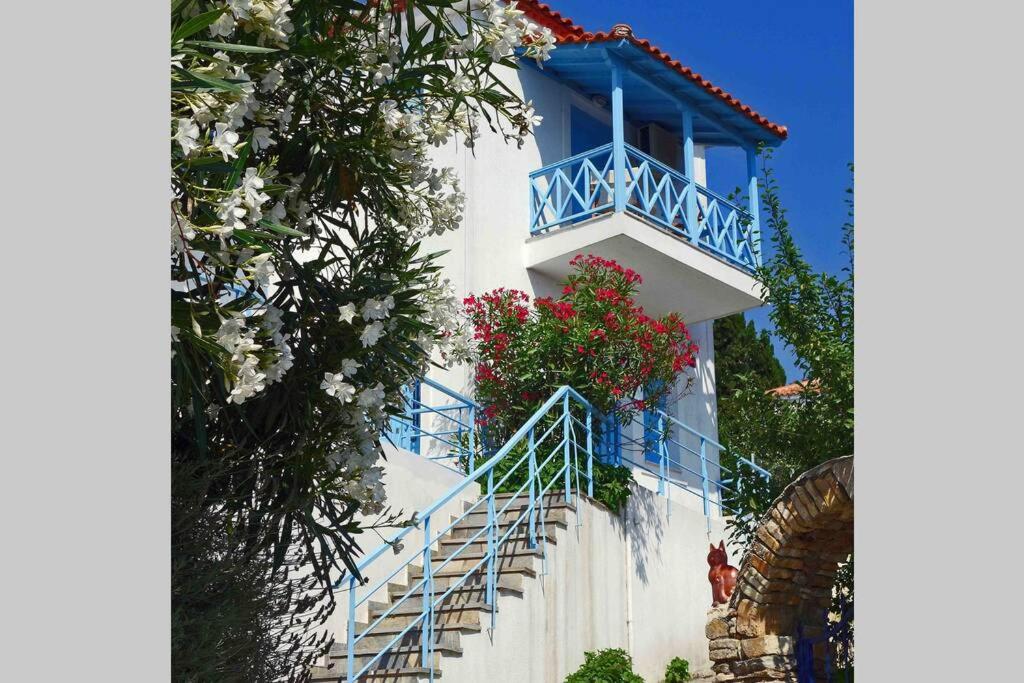 a blue and white building with a balcony with flowers at ELECTRA TRADITIONAL HOUSE in Alonnisos