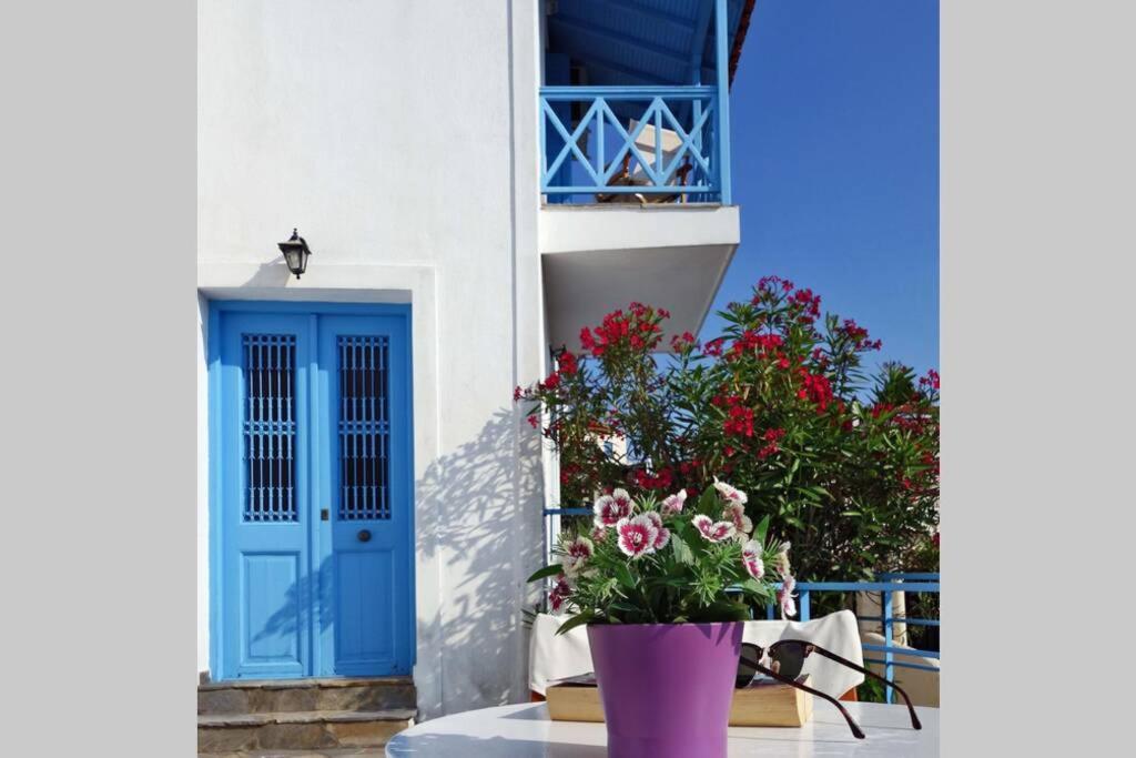 Fioletowa waza z kwiatami przed niebieskimi drzwiami w obiekcie ELECTRA TRADITIONAL HOUSE w mieście Alonissos-Chora