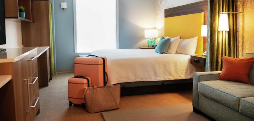 a hotel room with a bed and a couch and luggage at Home2 Suites By Hilton Elkhart in Elkhart