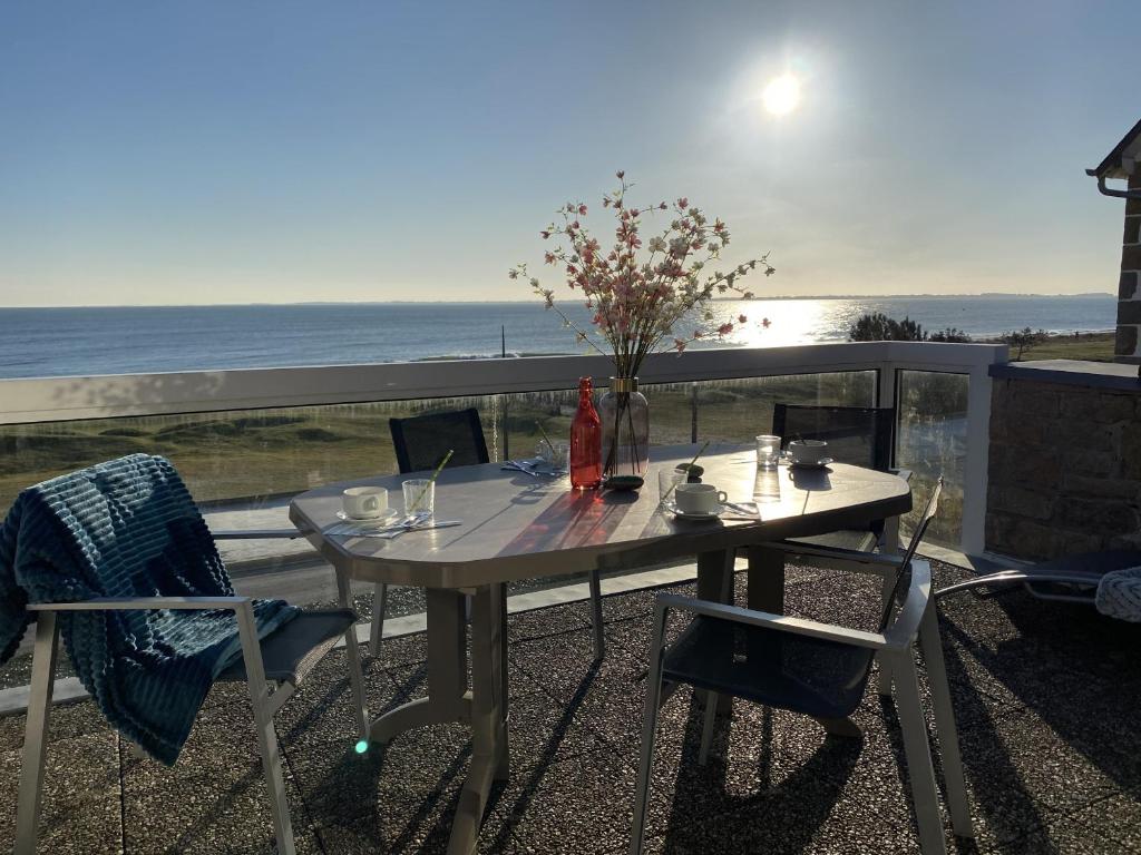 une table et des chaises sur un balcon avec vue sur l'océan dans l'établissement AZUR - Triplex spacieux, Face à la mer, Plage - T1, à Carnac