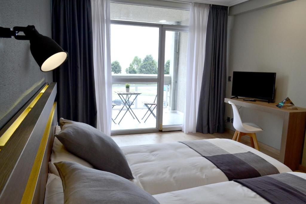 Habitación de hotel con cama y ventana grande en Hotel Alda Sada Marina en Sada