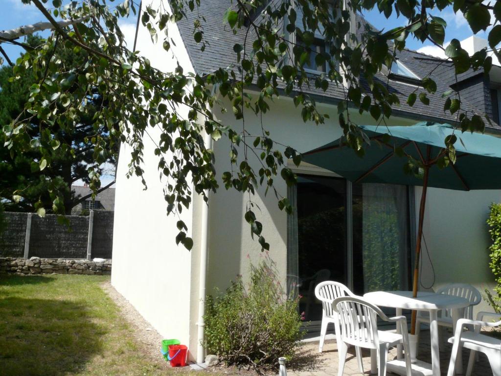 een patio met een tafel en stoelen en een parasol bij Ty Kreisker in Carnac