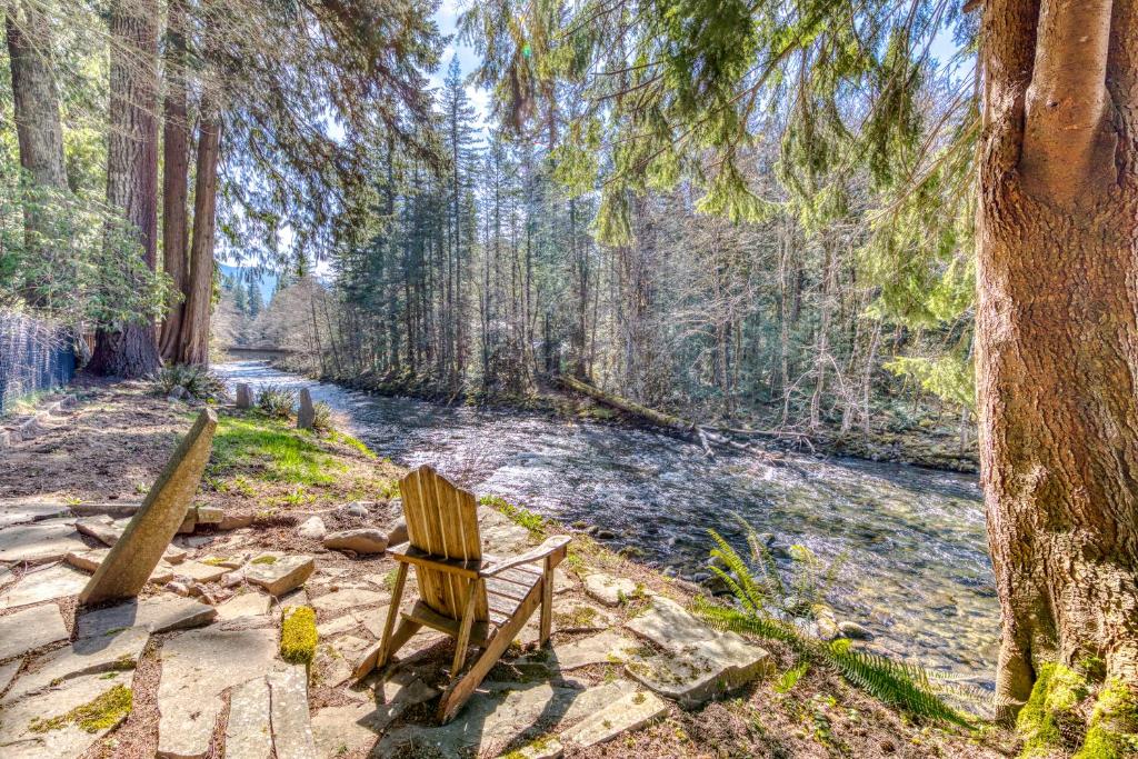 two wooden chairs sitting next to a river at Retreat on the Salmon River in Welches