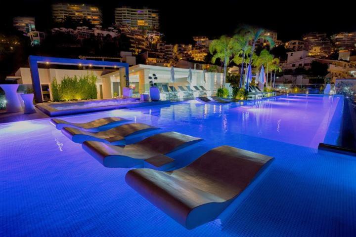 a swimming pool with several beds in it at night at Departamento Zona Romantica in Puerto Vallarta