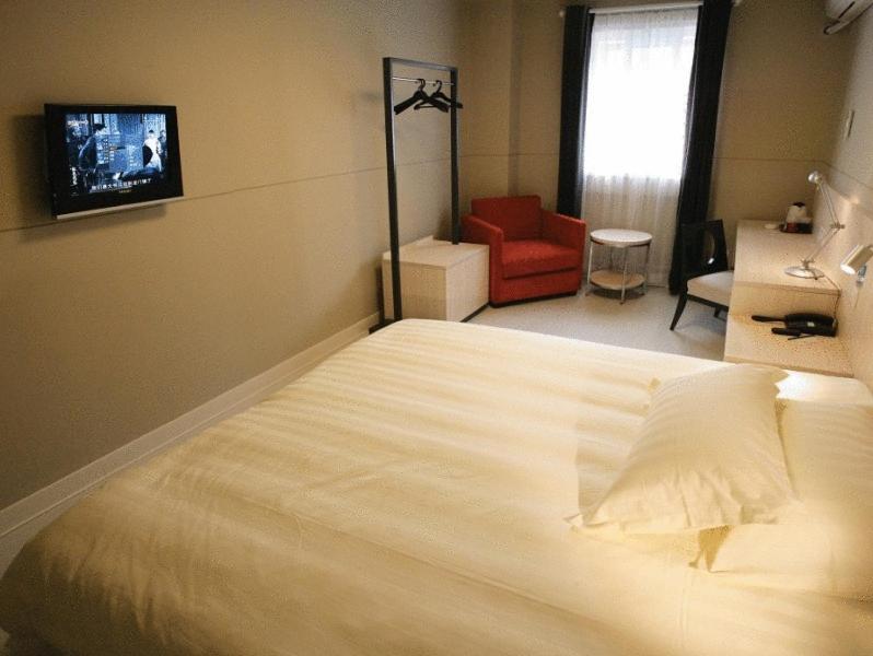 1 dormitorio con 1 cama blanca grande y 1 silla roja en Jinjiang Inn - Shanghai Changning en Shanghái