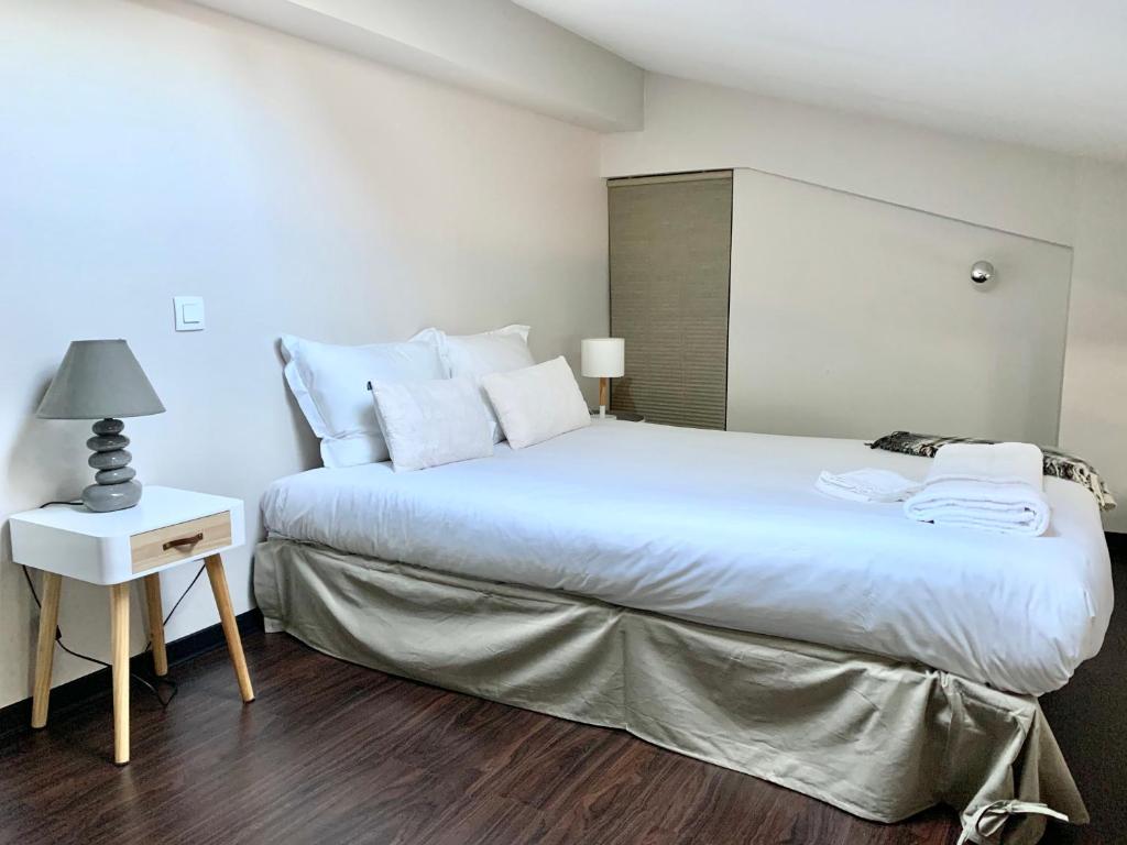 a bedroom with a large white bed and a night stand at L'Esquirol - Duplex design en hypercentre in Toulouse