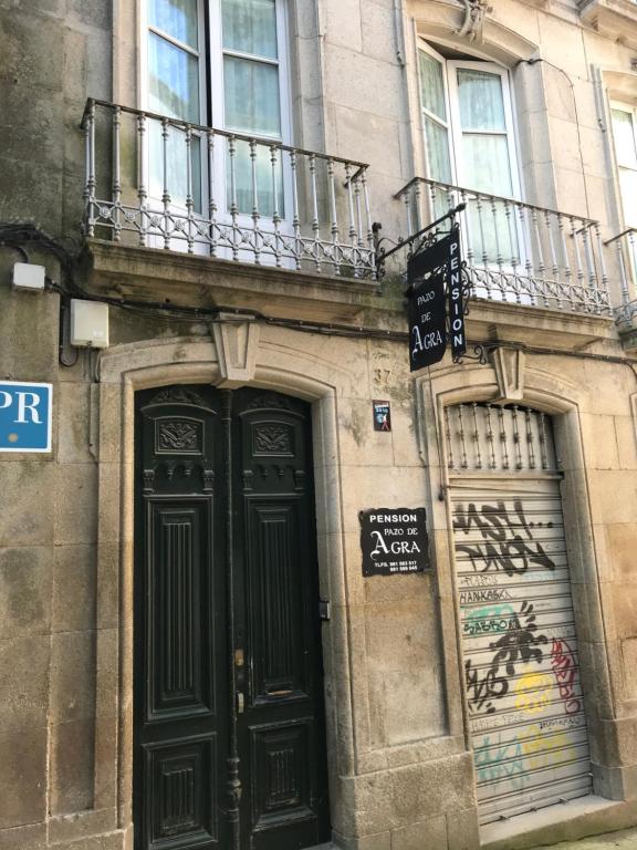 un edificio con porta nera e balcone di PR Paz de Agra a Santiago de Compostela