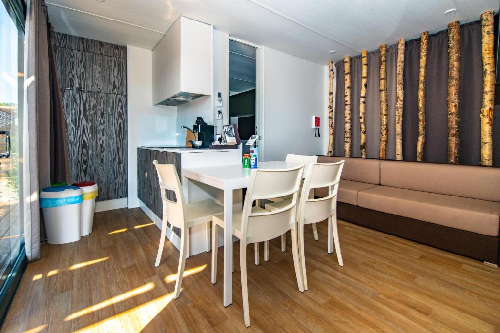 a kitchen and dining room with a white table and chairs at Arena Grand Kazela Camping Homes in Medulin