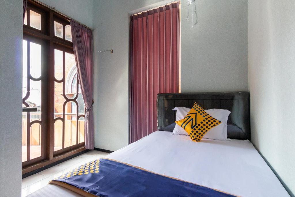 een slaapkamer met een bed en een groot raam bij SPOT ON 2689 Safira Family Residence Syariah in Lawang