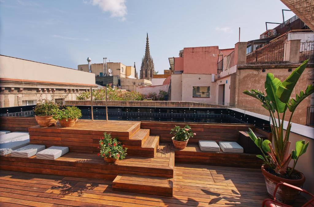 um deque no último piso com degraus de madeira e vasos de plantas em Casa Neri Apartments em Barcelona