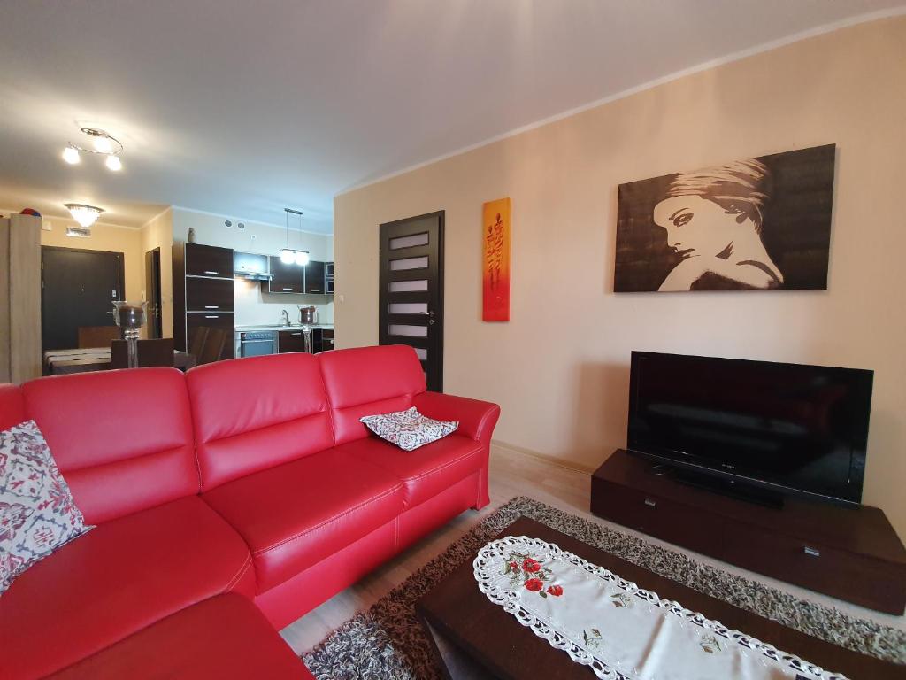 a living room with a red couch and a flat screen tv at Apartament w Porcie - 365PAM in Kołobrzeg