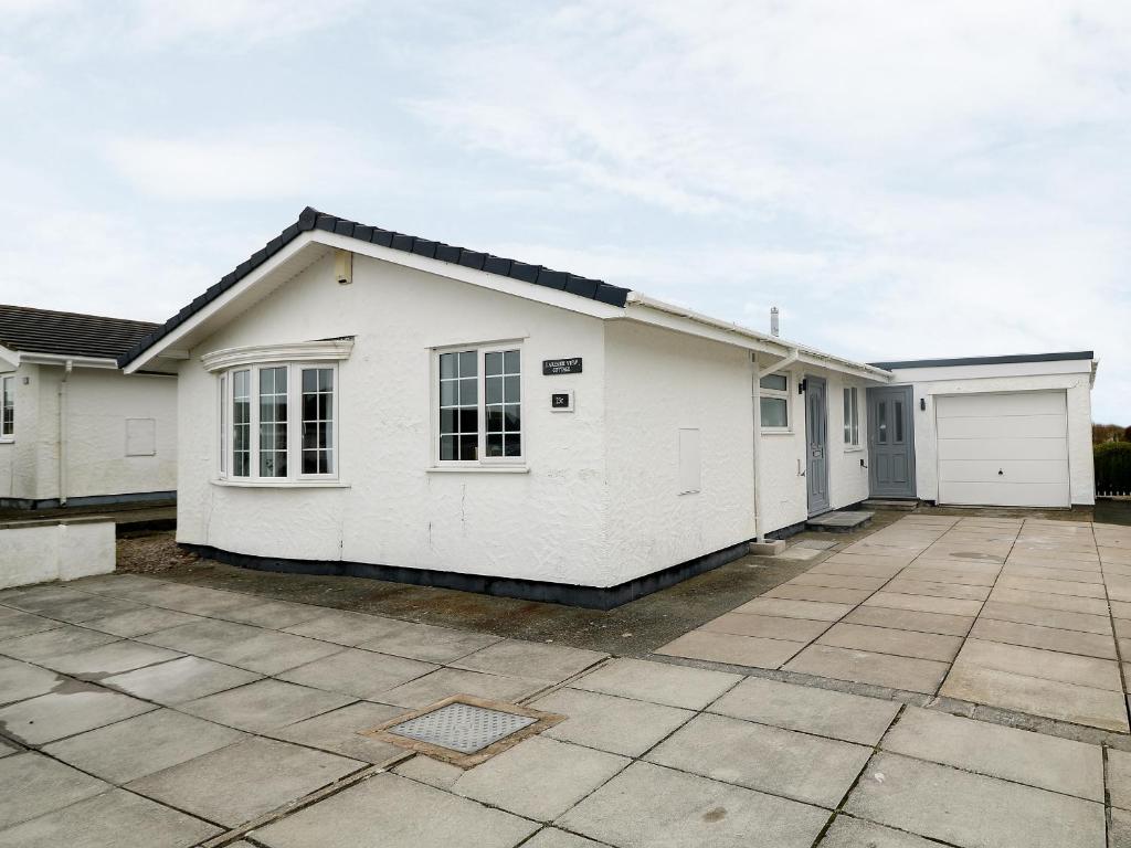 a white house with two garage at Lake View Cottage in Rhosneigr